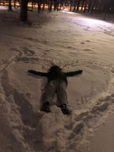 a person laying in the snow with their arms spread out to form a heart shape