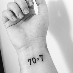 a person with a small tattoo on their wrist that reads 70x107 and has the number seventy