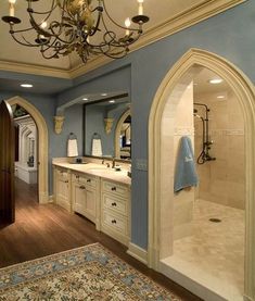 a large bathroom with blue walls and white fixtures, including a chandelier over the bathtub