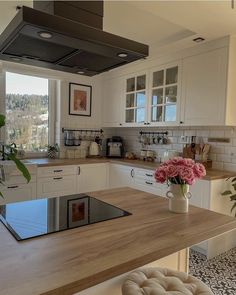 a kitchen with white cabinets and wood counter tops, an oven hood over the stove