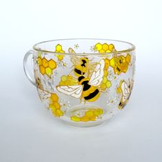 a glass bowl with yellow and black bees on it's rim, sitting on a white surface