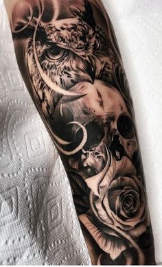 an owl and roses tattoo on the arm is shown in black and grey colors with white accents