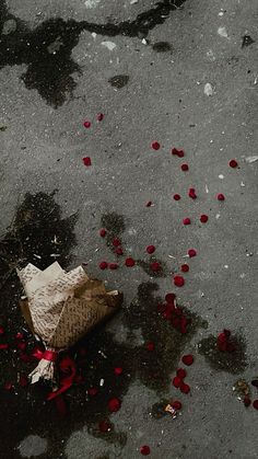 a paper bag and rose petals on the ground next to a puddle with water in it