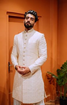 a man standing in front of a door wearing a white suit