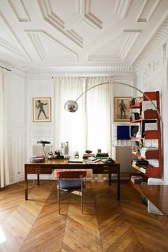 a room with wooden floors, white walls and a large desk in the middle of it