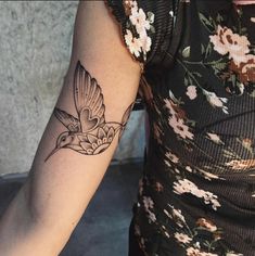 a woman with a tattoo on her arm holding a flower and bird in the air