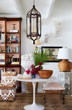 a living room filled with furniture and a lamp hanging from the ceiling next to a bookshelf