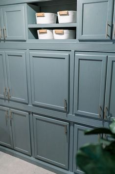 the cabinets in this kitchen are painted blue and have white baskets on top of them