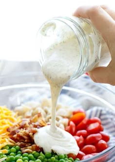 a person pouring ranch dressing into a bowl of food