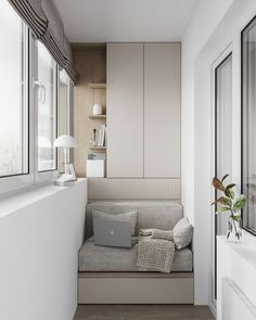 a white room with a laptop on the window sill next to a couch and bookshelf