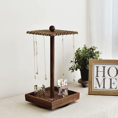 a wooden jewelry stand on top of a table next to a framed photograph and potted plant