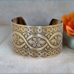 Solid BRASS Cuff, Brass Cuff Interlocking Flower Design, Lacquered Brass Cuff Bracelet, Brass Cuff Bracelet □ Antiqued Brass Cuff - 1 Piece □ Size: 1.5 inches wide - Interlocking Flower design □ Adjustable SOLID BRASS, not plated Stunning detail on these beautiful embossed cuffs. These are very sturdy but adjustable The tooling dates back to the 1940s and cannot be duplicated in today's market. Unlike my raw cuff collection, these special pieces are hand antiqued, hand polished and have a baked lacquer coating for a long lasting look and durability. They have a beautiful embossed interlocking flower design and are proudly Made in USA. To keep the beautiful lacquer finish & beautiful luster, it is not recommended to immerse in water.  Please visit my sister shop ▶︎ https://www.etsy.com/shop Brass Cuff Bracelet, Brass Cuff, Flower Design, Cuff Bracelet, Antique Brass, Flower Designs, Solid Brass, Cuff Bracelets, 1 Piece