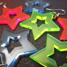 "A throwback to a time of Big Hair and Big Style - These Neon Star Earrings Catches Eyes and Glows in Black light! ★ YOU PICK which neon color you like best! All Big Star Cutout Earrings are made of laser cut neon pink, green OR blue acrylic. ★ Surprisingly lightweight, each Radiant Star Pendant measures 1.25\" wide and hangs on your choice of earring hooks! Pick from: ~ Nickel Free (Shown in Pictures) ~ Stainless Steel ~ Plastic Hooks ~ Clip Ons ~ Titanium Hooks ★ These Cutout Star Earrings mak