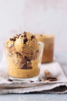 two desserts with ice cream and chocolate chips in glass bowls on top of a napkin