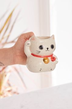 a hand holding a white ceramic cat figurine