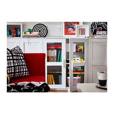 a red chair sitting in front of a white book shelf