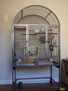 a large bird cage sitting on top of a metal stand