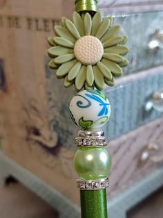 a close up of a green bottle with a flower decoration on it's top