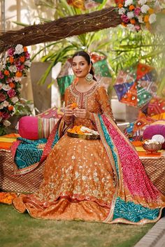 a woman sitting on top of a bed in an orange and pink dress with flowers