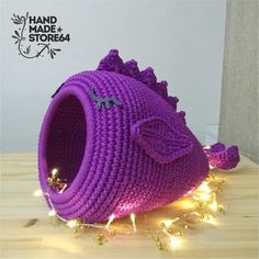 a purple crocheted cat bed with lights around it