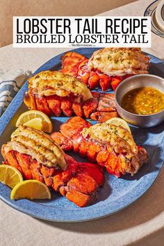 lobster tails on a blue plate with dipping sauce and lemon wedges next to it