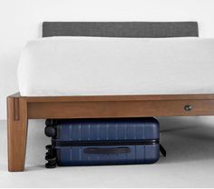 two pieces of luggage under a bed with a wooden frame and foot board on the bottom