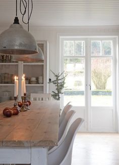 a dining room table with candles and apples on it in front of an open door