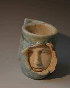 a ceramic vase with a face in the middle and a hole in the side to show it's inner workings