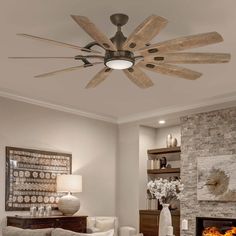 a living room filled with furniture and a fire place under a ceiling fan in front of a stone fireplace