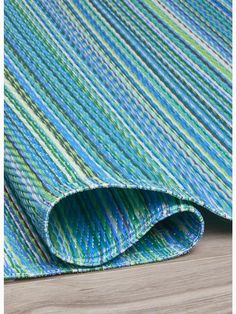 a blue and green striped rug on top of a wooden floor next to a wall