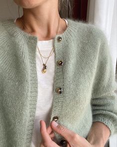 a woman is wearing a green cardigan and holding her hands out to the side