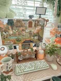 there is a computer on the desk with many flowers and plants in front of it