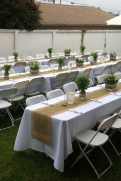 tables and chairs are set up in the yard for an outdoor event with white tablecloths