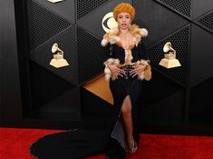 a woman in a black dress and fur stoler on the red carpet at an awards event