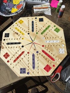 a wooden board with different colored pegs on top of it and scissors next to it