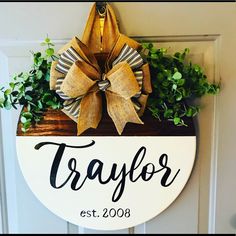 a door hanger with a bow on it that says taylor est 2008 and is decorated with greenery