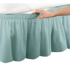 a person is holding their bed skirt open