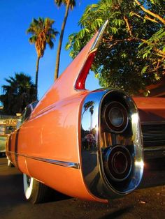 an orange classic car parked in front of palm trees