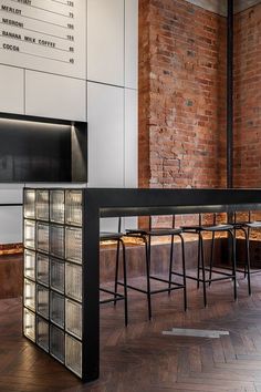 an empty bar with four stools and a menu on the wall