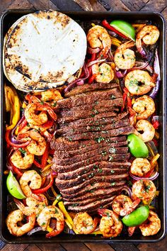 steak, shrimp and peppers on a tray with a tortilla in the background