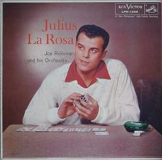 a man sitting at a desk with his hands in front of him and the words john la rose on it