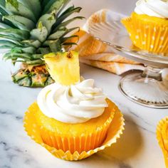 pineapple cupcakes with white frosting on a marble table