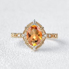 an orange and white diamond engagement ring on a white surface with the top half cut off