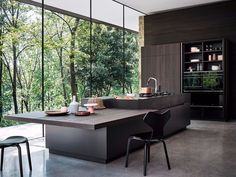 a modern kitchen with an island counter and black chairs in front of the open window