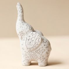 an elephant figurine made out of white clay with intricate designs on it's trunk