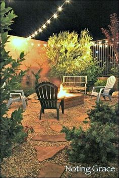 an outdoor fire pit and seating area with string lights strung over the patio at night