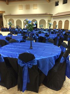 a banquet hall with tables covered in blue and black cloths, decorated with flowers