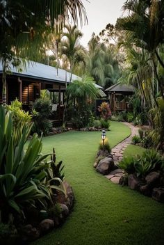 a lush green yard surrounded by trees and rocks with a path leading to the house