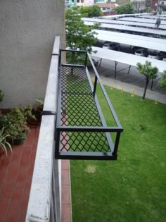 an iron railing on the side of a building with green grass and buildings in the background