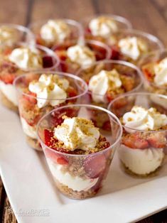 small desserts with strawberries and whipped cream are arranged on a white platter